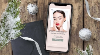 telefon na drewnianym stole w otoczeniu zielonej iglastej galazki