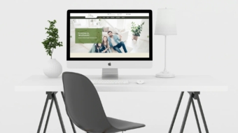 komputer lezacy na biurku krzeslo i kwiatek w tle